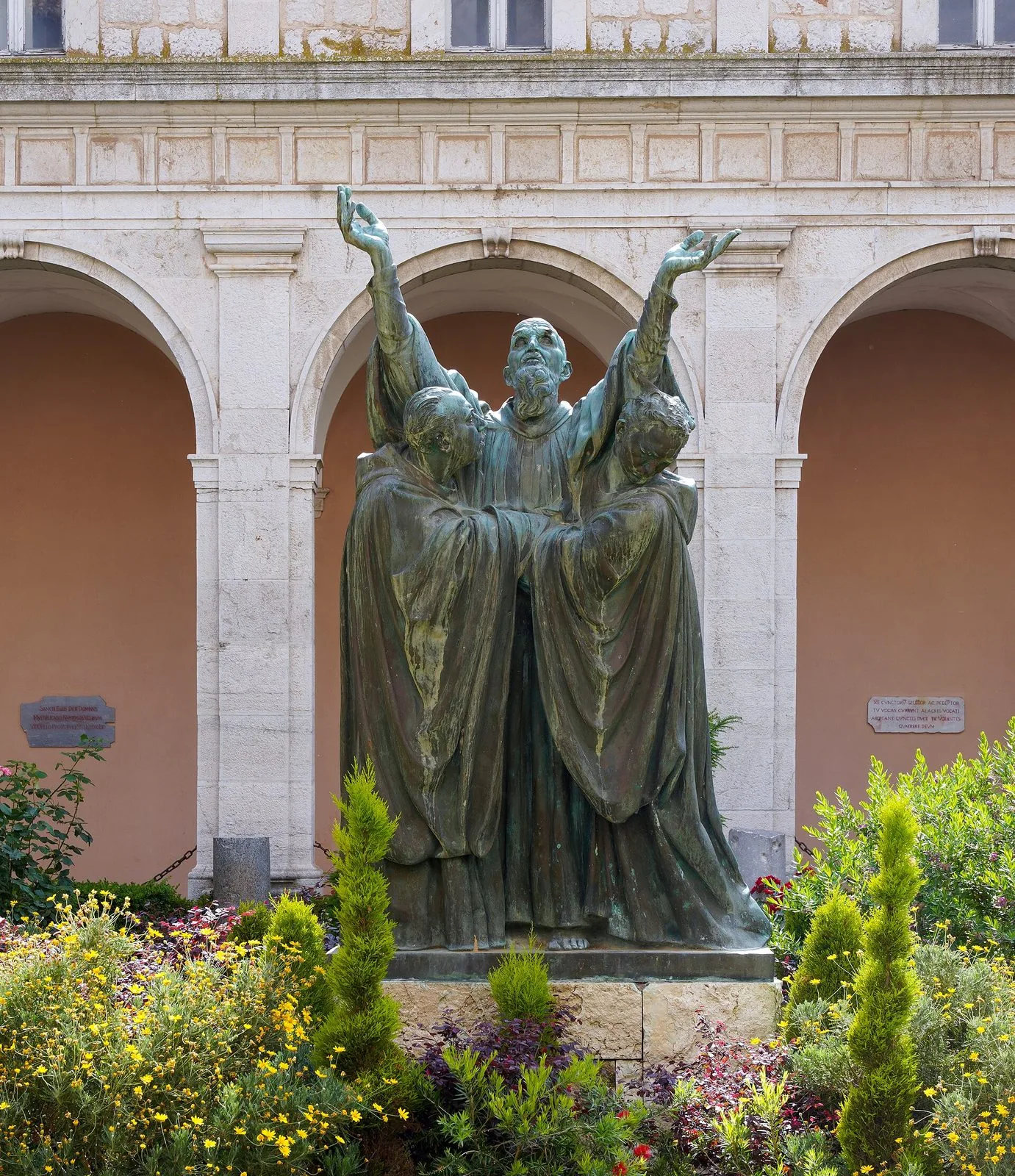 Statua in bronzo di San Benedetto con le braccia levate al cielo, sorretto da due monaci, in un chiostro dell'Abbazia di Montecassino